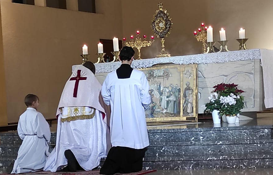 Adoration eucharistique, avec le prêtre agenouillé devant le Saint-Sacrement